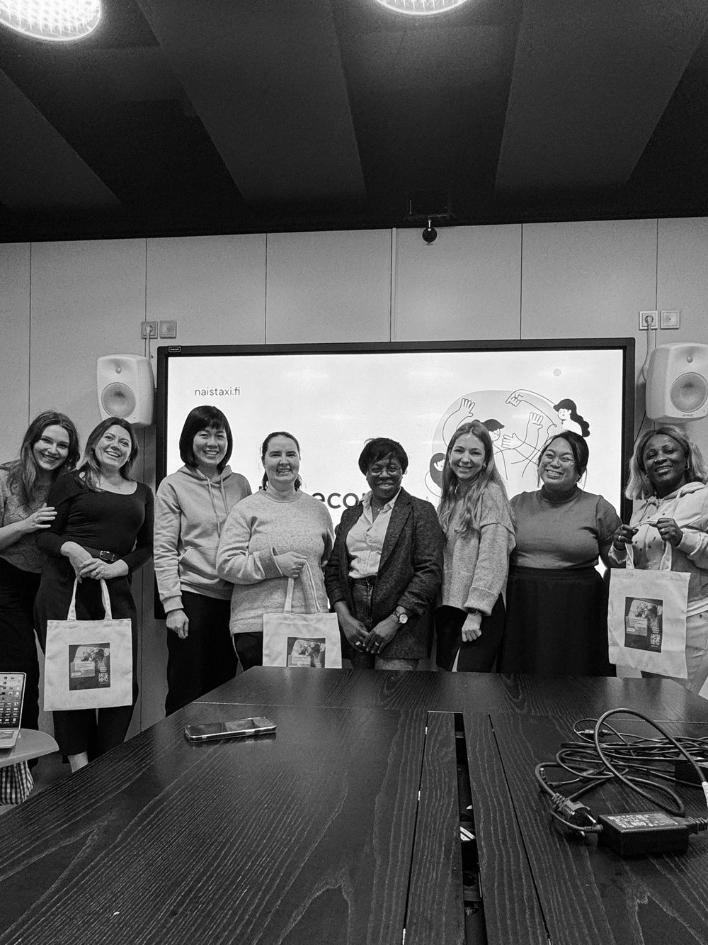 Eight members posing together with tote bags after a workshop