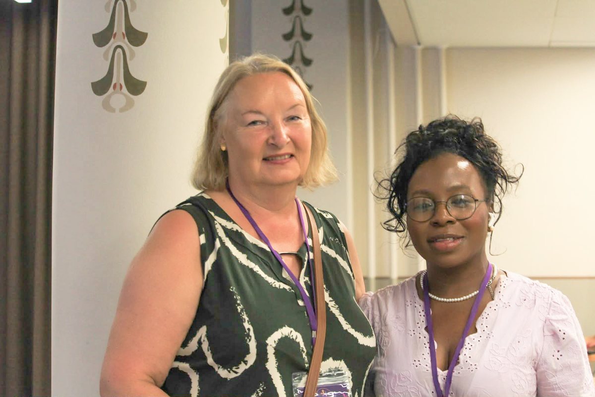 Two members wearing event lanyards, smiling together at a gathering